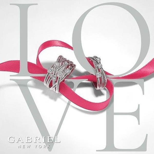 A clean, high-contrast 1:1 image featuring a diamond ring centered inside the word LOVE, highlighted by a vibrant pink ribbon.