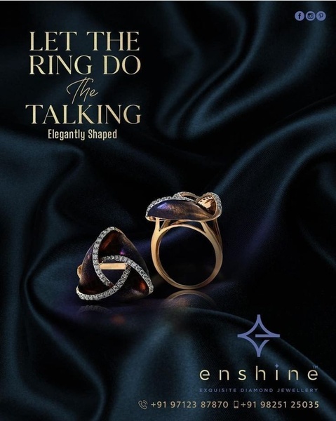A high-end advertisement showcasing two elegantly shaped diamond rings against a dark, silken fabric backdrop to emphasize luxury and texture.