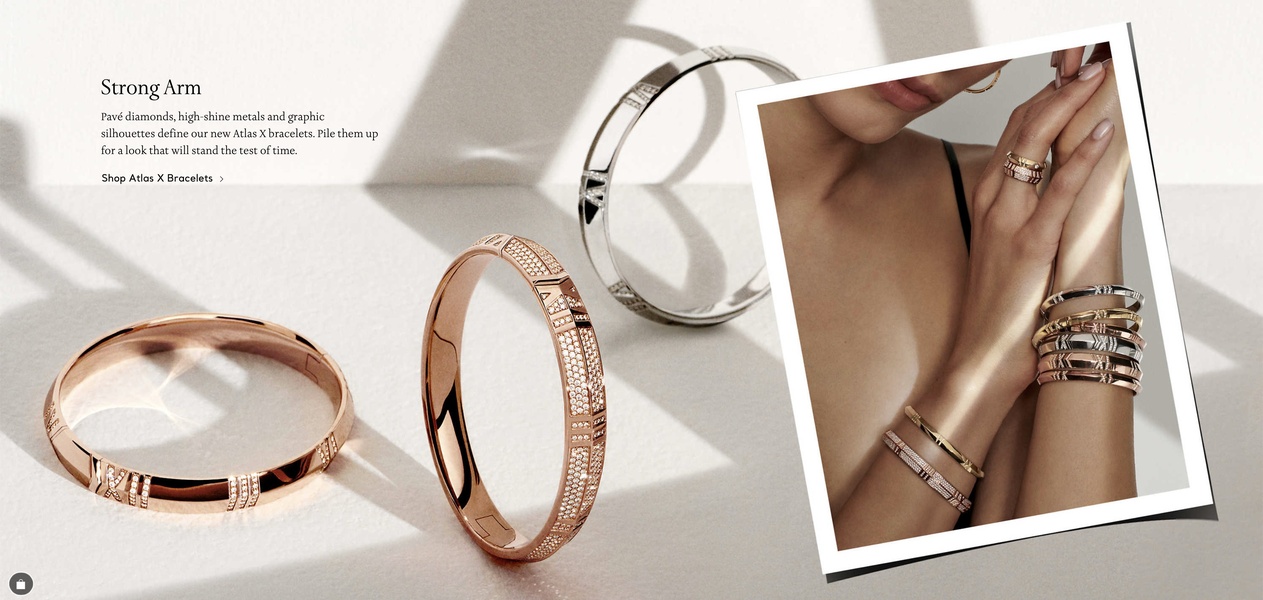 A high-end editorial display featuring multiple bracelets stacked on a wrist and presented in a clean, minimalist studio setting.