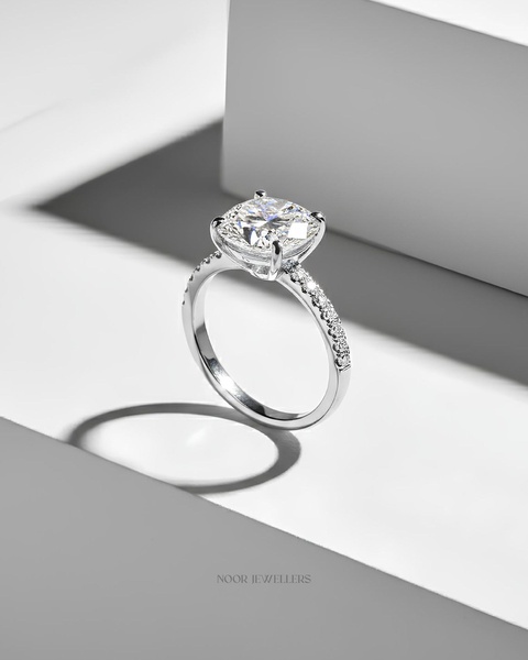 A high-end, studio-lit image of a diamond engagement ring placed on a white architectural pedestal, emphasizing luxury and clean lines.