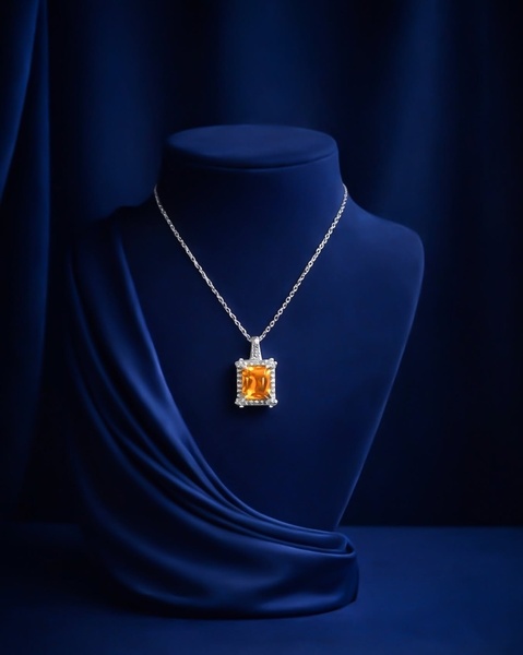 A high-end, studio-style product photograph of an orange rectangular gemstone pendant necklace displayed on a dark blue velvet bust.