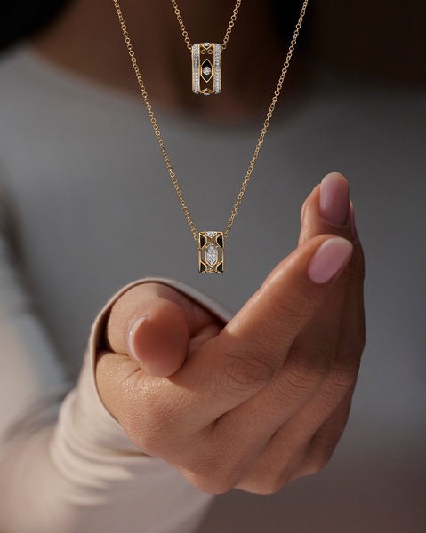 A high-end product photography shot featuring a necklace suspended in mid-air above a person's hand, emphasizing luxury and minimalist design.
