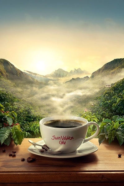 A high-quality 2:3 vertical ad featuring a steaming cup of coffee centered in a lush, misty mountain landscape during sunrise.