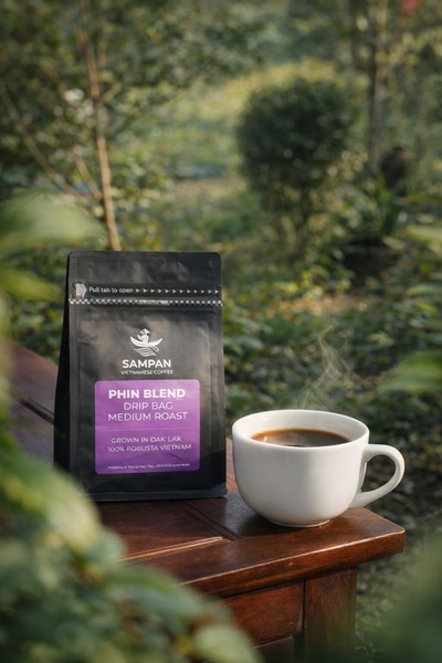 A high-quality, product-focused image featuring a single drip coffee bag and a steaming cup placed on a rustic table in a serene, natural outdoor setting.