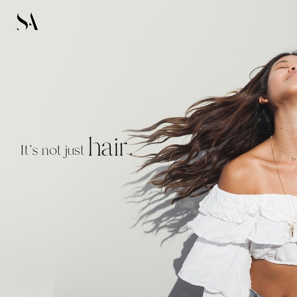 A high-end, minimalist lifestyle image featuring a woman with flowing hair and a bold brand claim overlaid in refined typography.