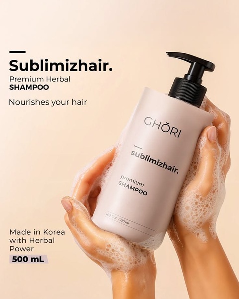 A close-up product shot featuring a bottle of herbal shampoo held in hands with lather, emphasizing a clean, premium brand aesthetic.