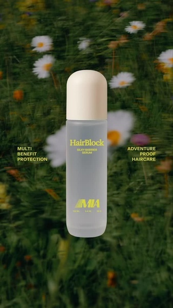 A clean, minimalist product shot of a serum bottle placed in a blurred outdoor meadow setting, emphasizing natural benefits and adventure-ready protection.