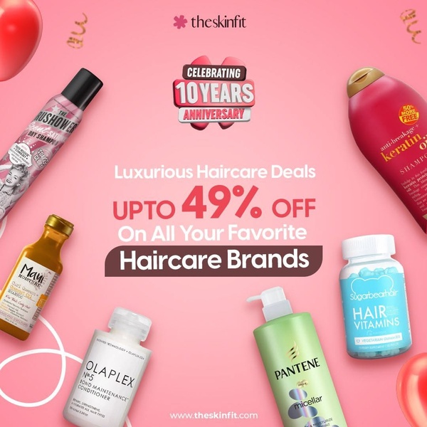 A flat-lay ad creative showcasing a variety of haircare products on a pink background to announce a brand anniversary discount.