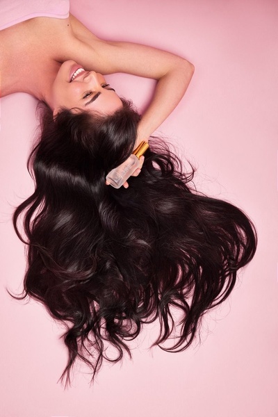 This creative features a woman lying down with her hair fanned out while holding a serum bottle, focusing on healthy, voluminous hair imagery.