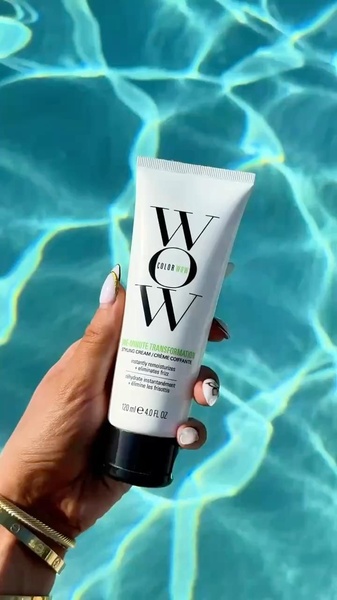 A close-up, high-contrast shot of a Styling Cream tube held against the vibrant blue background of a swimming pool.