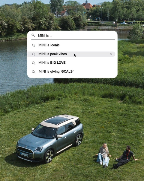 An electric SUV parked in a meadow featuring an overlay of a mock search bar with aspirational descriptors for the vehicle.