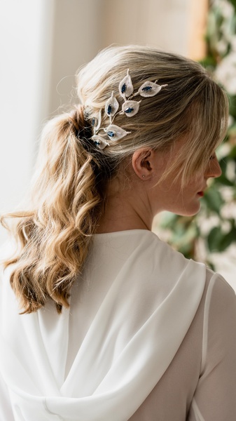 A close-up, high-quality portrait of a model wearing an elegant leaf-patterned hair pin, focusing on the product details and aesthetic appeal.