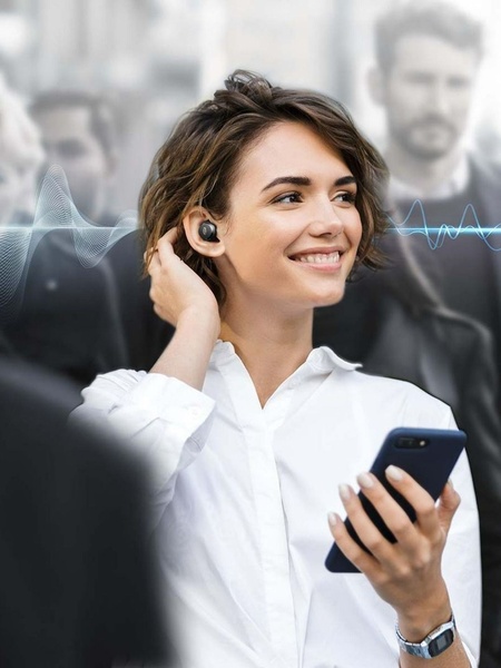 A close-up lifestyle shot of a smiling woman wearing wireless earbuds in a crowded environment, illustrated with subtle audio-wave graphics to symbolize noise cancellation.
