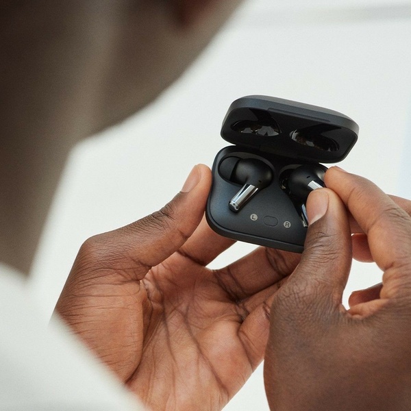 A close-up, high-detail shot showing hands placing wireless earbuds into their charging case to emphasize product design and quality.