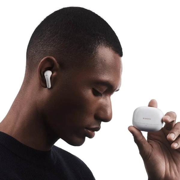 A high-contrast, professional product portrait of a man wearing wireless earbuds while holding the charging case, emphasizing sleek product aesthetics.