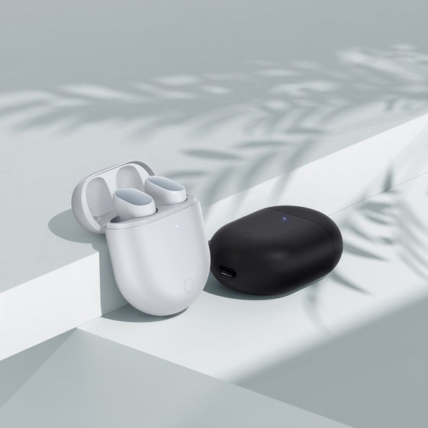 A high-end, clean product photography layout featuring white and black earbud cases on a soft-shadowed, neutral stage.