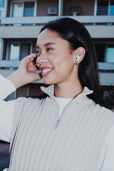 A close-up portrait of a woman wearing sleek wireless earbuds, emphasizing comfort and aesthetic appeal in a natural environment.