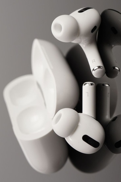 A clean, high-contrast studio shot of wireless earbuds paired with their charging case against a neutral gray background.