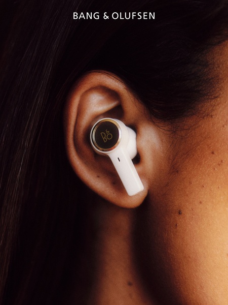 A high-end, extreme close-up shot focusing on the design and premium finish of a single earbud worn in a person's ear.