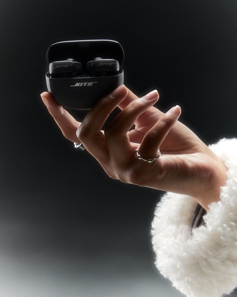 A close-up, high-contrast shot of a hand holding open wireless earbuds, focusing on brand placement and clean aesthetics.