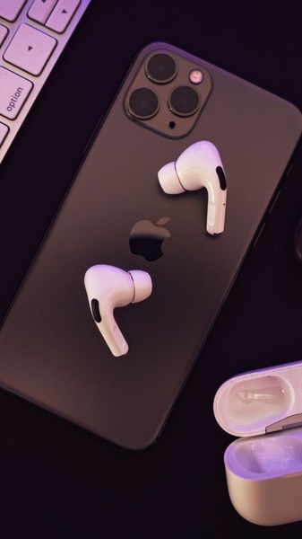 A top-down, high-contrast flat lay composition featuring wireless earbuds and a smartphone, utilizing soft ambient purple lighting.