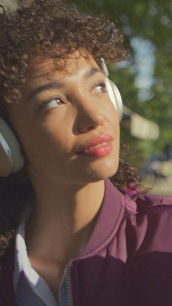 A close-up portrait of a woman wearing modern over-ear headphones during the golden hour, creating an aspirational and high-end brand feel.
