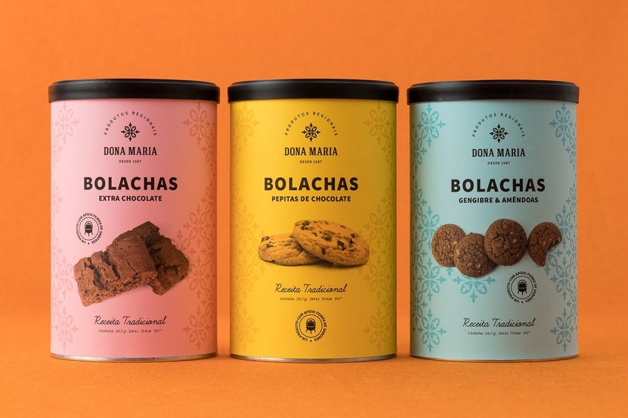 A high-quality, front-facing product shot of three distinct cookie tin flavors arranged symmetrically against a bold, solid orange background.