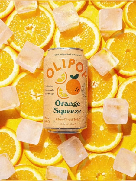 A vibrant 3:4 vertical ad featuring a can of Orange Squeeze soda surrounded by sliced oranges and melting ice cubes on a bright yellow background.