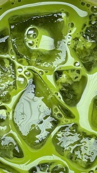 A high-definition, top-down shot of a refreshing matcha latte filled with ice cubes, highlighting the vibrant green texture and condensation.