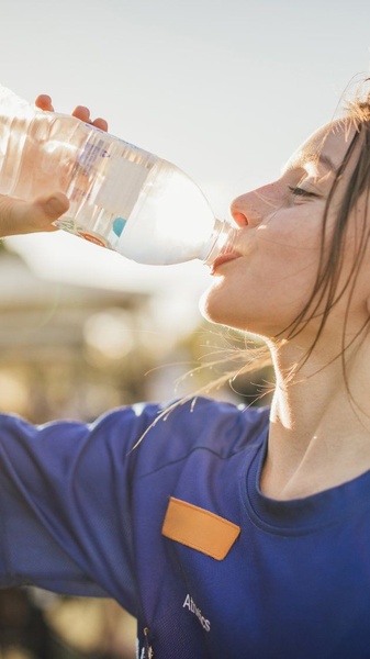 A close-up, sun-drenched shot of an athlete drinking from a water bottle, emphasizing performance and refreshment.