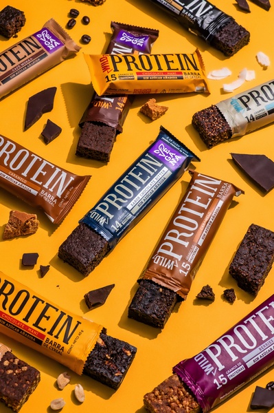 A top-down, structured flat lay photography style featuring multiple protein bar flavors organized against a vibrant solid yellow background.