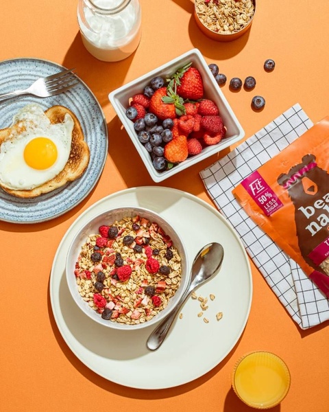 A top-down view of a balanced breakfast set including a bowl of granola with berries, toast with an egg, and a serving of milk.