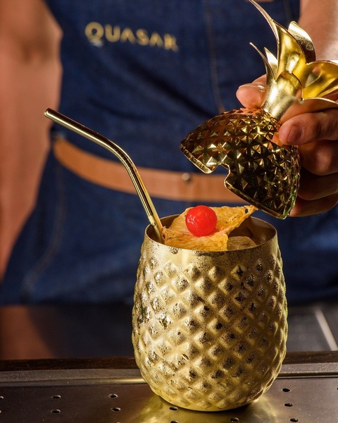 A high-end cocktail served in a golden pineapple-shaped vessel, capturing the essence of luxury beverage branding.