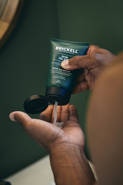 A close-up shot capturing a person dispensing natural face scrub into their palm, emphasizing the product texture and brand identity.