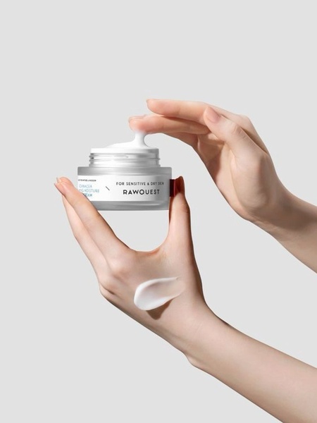 A clean, high-key studio product shot showcasing the texture and application of a moisture cream held by human hands.
