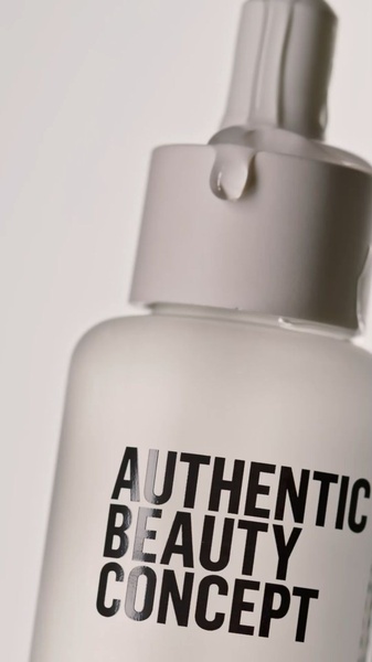 A close-up, high-key studio photograph of a serum bottle with a clear drop of liquid hanging from the dropper, emphasizing product purity.
