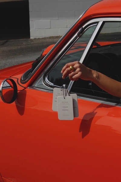 car air freshener, hanging fragrance tag, scented car tag, car scent, hanging scent diffuser, brand awareness, lifestyle, editorial, calm, luxurious, red, neutral